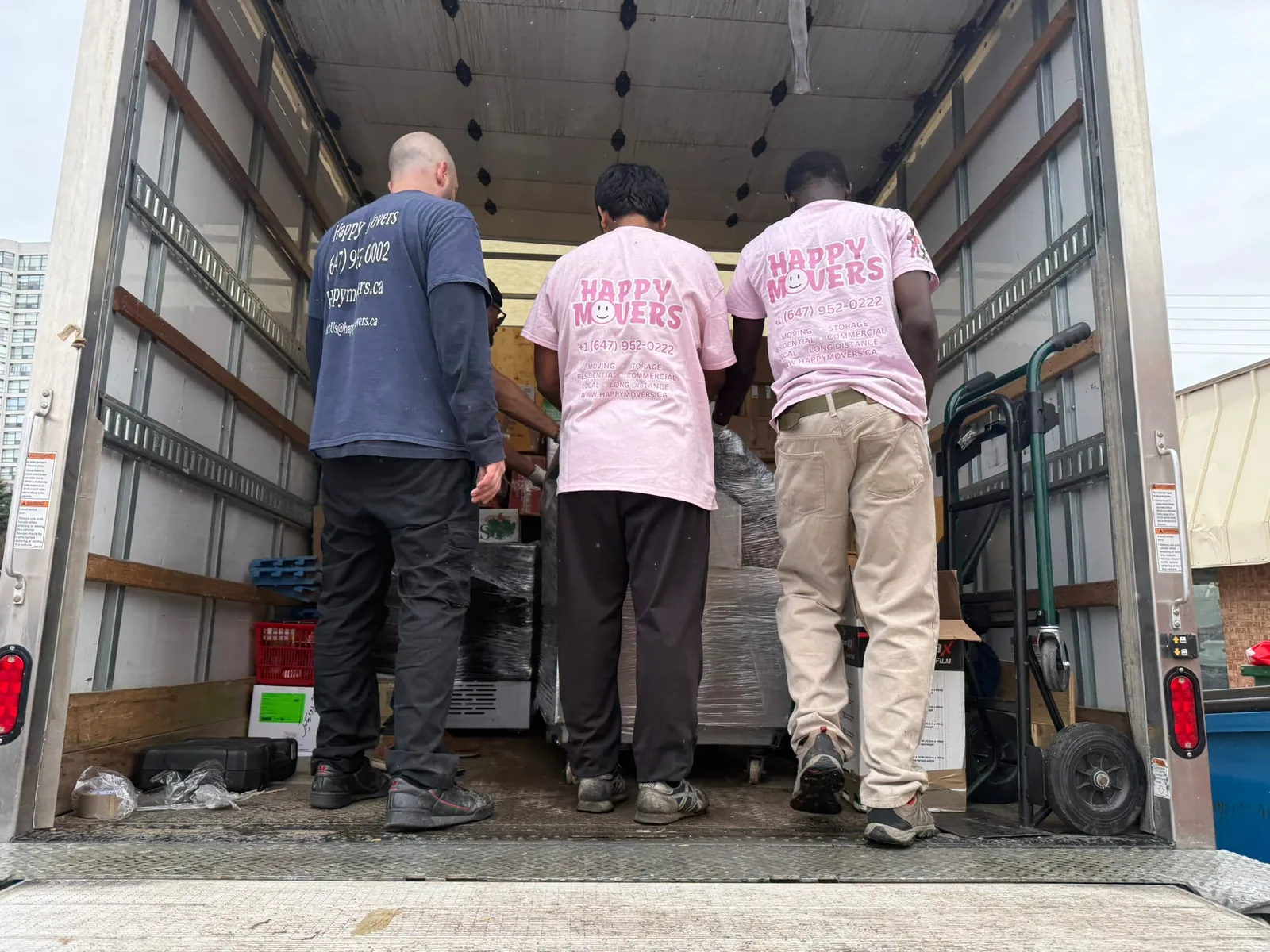 Happy Movers crew loading wrapped furniture into a moving truck